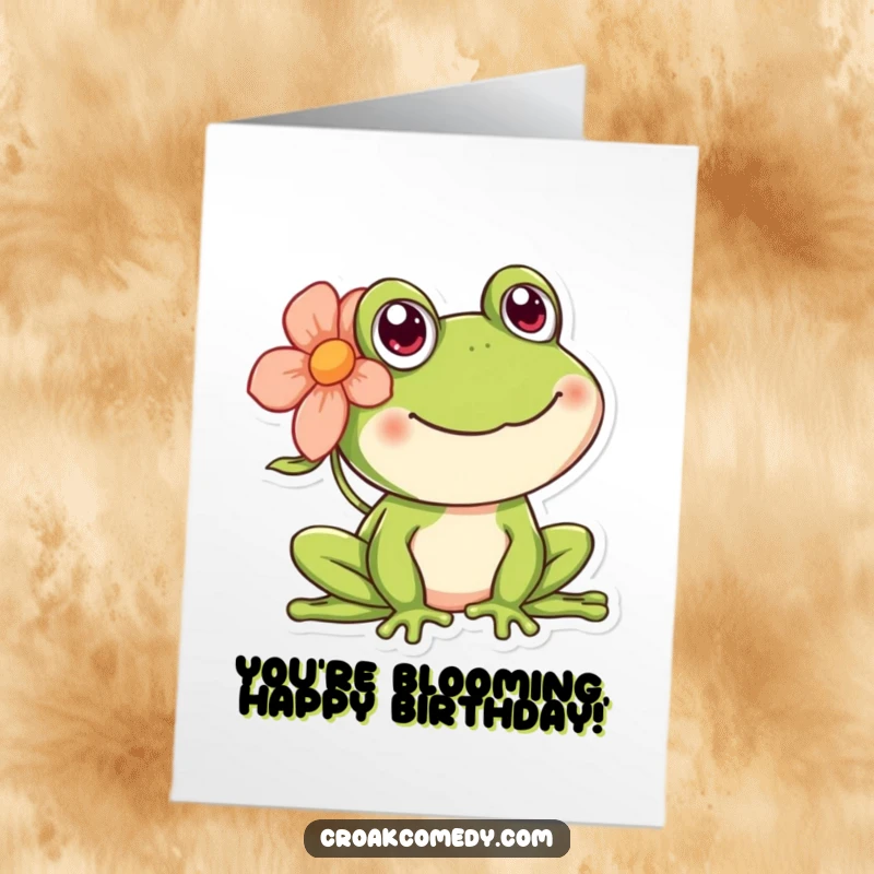 Free Printable Birthday Card showing a happy frog wearing a colorful flower behind its ear, radiating joy.